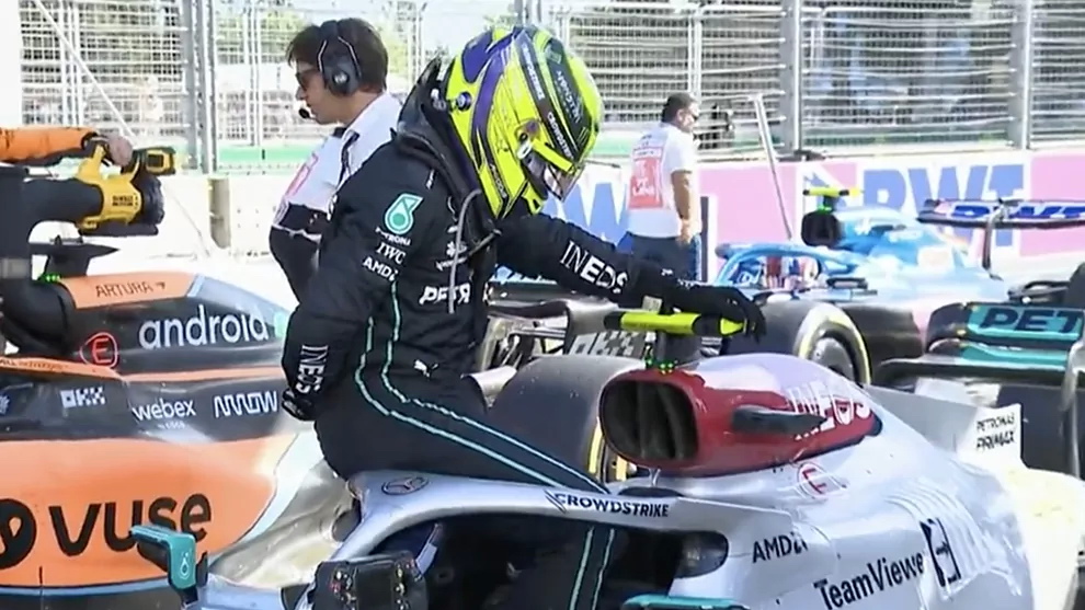 Lewis Hamilton pomalu vystupuje z vozu, drží se za bolavá záda